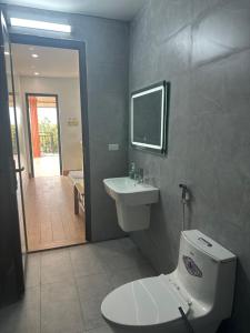 a bathroom with a toilet and a sink and a mirror at Bong Mai Thai Hoa Hotel in Làng Dương