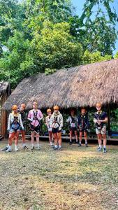 a group of people standing in front of a hut at Namdong Waterfall & Eco Resort in Luang Prabang