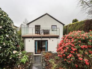 a white house with a balcony and some flowers at Striding Home in Ambleside