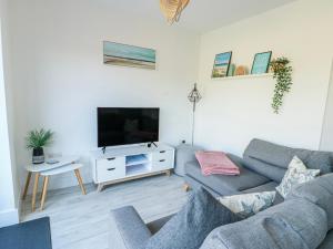 a living room with a couch and a tv at Dune Retreat in Rhosneigr