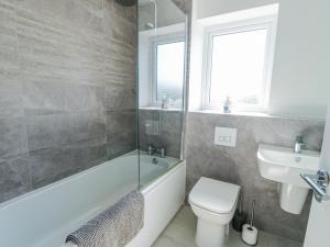 a bathroom with a tub and a toilet and a sink at Dune Retreat in Rhosneigr +12 photos