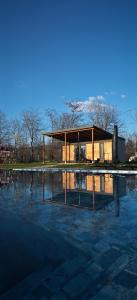 a house sitting on top of a pool of water at Badash Tiny Village - Tiny Houses with Heated Pool & BBQ in Polovragi