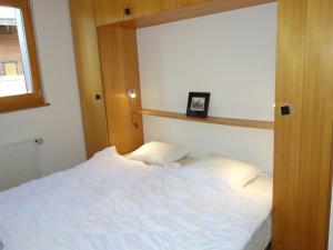 a bedroom with a white bed with a wooden headboard at Cozy apartment for groups in Veysonnaz
