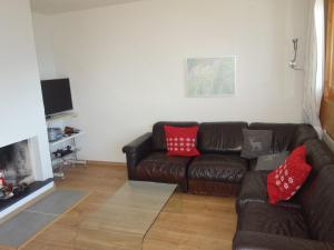 a living room with a brown leather couch with red pillows at Cozy apartment for groups in Veysonnaz