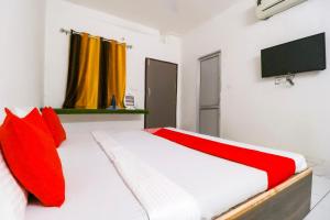 a bedroom with a bed with red pillows and a tv at Hotel O Sky Garden in Ludhiana