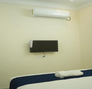 a room with a bed and a tv and a pillow at La Coral Residency in Pondicherry