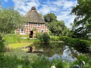 an old building with a pond in front of it at Haus Siebenstein Living for a good cause in Drochtersen