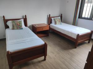 two twin beds in a room with a night stand at mahogany villa in Grand-Baie