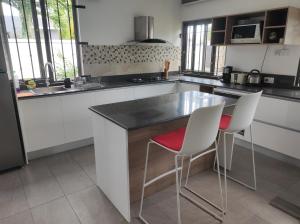 a kitchen with a counter and two white chairs at mahogany villa in Grand-Baie