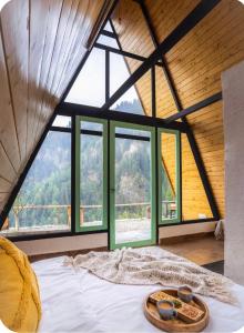 a bed in a room with a large window at Tri peak Cottage in Jibhi