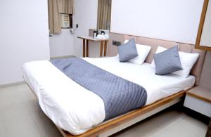ein Schlafzimmer mit einem großen Bett und blauen Kissen in der Unterkunft Hotel Excellency in Dīsa