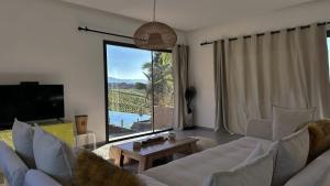 a living room with a white couch and a large window at Kaha Lak in Douar Aguergour