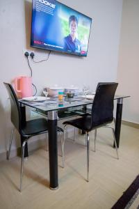 a table with chairs and a tv hanging on a wall at Vine Suites Mbarara Fully Furnished 1BR - Ideal for Short & Long Stays in Mbarara +6 photos