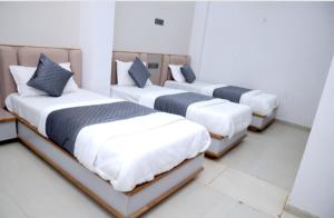 eine Gruppe von drei Betten in einem Zimmer in der Unterkunft Hotel Excellency in Dīsa