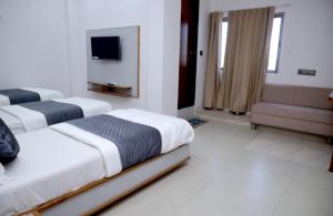 ein Hotelzimmer mit drei Betten und einem Fernseher in der Unterkunft Hotel Excellency in Dīsa