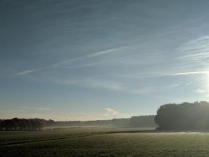 a misty field with the sun in the sky at Maison Malo in As