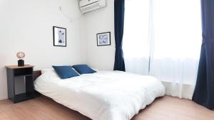 a white bed with blue pillows in a bedroom at MSTAY池袋one in Tokyo