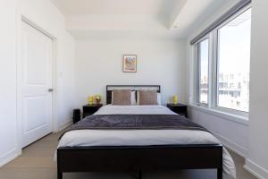 a bedroom with a large bed and two windows at Downsview Park Luxury Townhome near Yorkdale Transit in Toronto