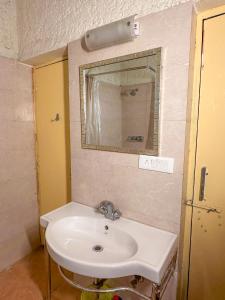 a bathroom with a white sink and a mirror at Bird Songs in Rāmgarh