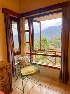 a chair in front of a window with a view at Bird Songs in Rāmgarh +12 photos