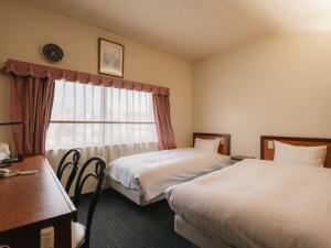 a hotel room with two beds and a window at Hotel Union in Kagoshima