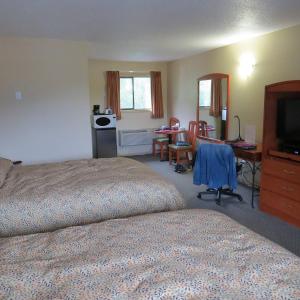a bedroom with a bed and a desk and a television at Retasket Lodge & RV Park in Lillooet