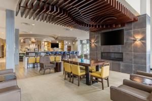 a dining room with a table and a tv on a wall at Cambria Hotel Denver International Airport in Aurora