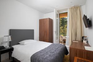 a bedroom with a bed and a desk and a window at Brijuni Hotel Neptun in Fažana