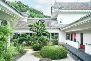 a garden in front of a building with a tree at Tabist Yuasa Castle Onsen Hotel in Yuasa