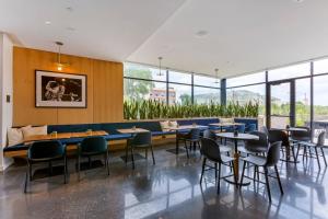 a restaurant with tables and chairs and windows at Cambria Hotel Austin Airport in Austin