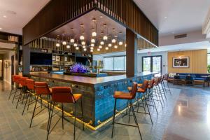 a bar in a restaurant with orange stools at Cambria Hotel Austin Airport in Austin