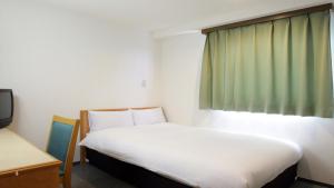 a bedroom with a white bed and a window at Hotel Green Palace in Sendai