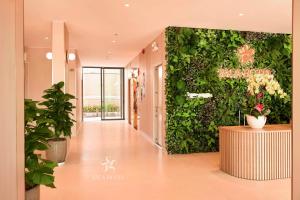 a hallway with a green wall with plants at Sala Hotel Phan Thiet in Phan Thiet