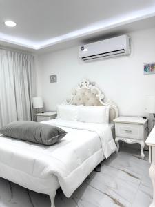 a white bedroom with a large white bed with a white headboard at Velmora 1BR Apartment 13 in Abu Dhabi