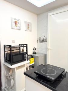 a kitchen with a black counter top with a microwave at Velmora 1BR Apartment 13 in Abu Dhabi