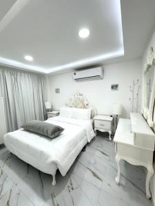 a white bedroom with a large bed and a desk at Velmora 1BR Apartment 13 in Abu Dhabi