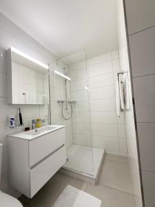 a white bathroom with a shower and a sink at HRE Apartments Rorschach - Self Check-In in Rorschach +37 photos
