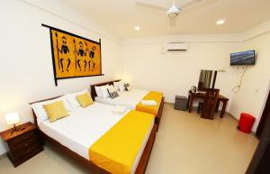 a bedroom with two beds and a television in it at Hotel Emerald Green in Weligama +50 photos