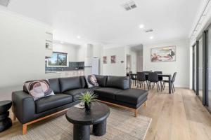 a living room with a black couch and a table at Riversands Rest Accommodation Scenic Riverfront Cottages, Paringa in Renmark