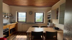 a kitchen with a table and chairs and two windows at Pension Highway - Bünde Vincke Straße 11 in Bünde