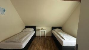two beds in a room with a side table at Pension Highway - Bünde Vincke Straße 11 in Bünde