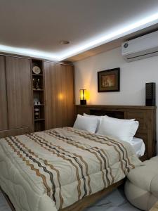 a bedroom with a large bed with a striped blanket at Velmora Villas Room 12 in Abu Dhabi