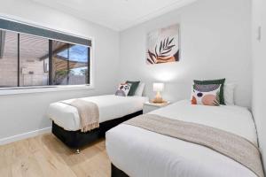 two beds in a white room with a window at Riversands Rest Accommodation Scenic Riverfront Cottages, Paringa in Renmark