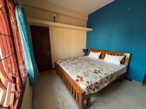 a bedroom with a bed with a blue wall at IP - Malar in Pondicherry