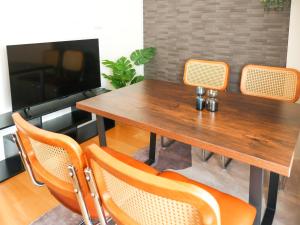 a wooden table with orange chairs and a television at MSTAY池袋one in Tokyo