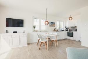 a kitchen with white cabinets and a white table and chairs at Boddenruh in Fuhlendorf