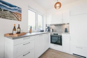 a kitchen with white cabinets and a counter with wine bottles at Boddenruh in Fuhlendorf