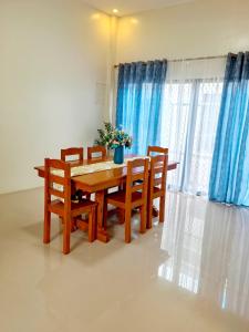 a dining room table and chairs with blue curtains at Villa Emee Nora in Panglao Island