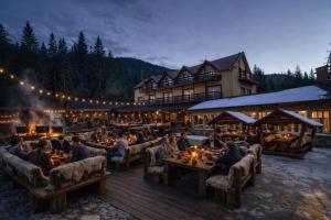 a group of people sitting at tables in front of a lodge at POARTA PADINA, statiunea Pestera-Padina, Bucegi in Moroeni