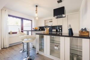a kitchen with white cabinets and a counter with a stool at Gartenidyll in Zingst +25 photos